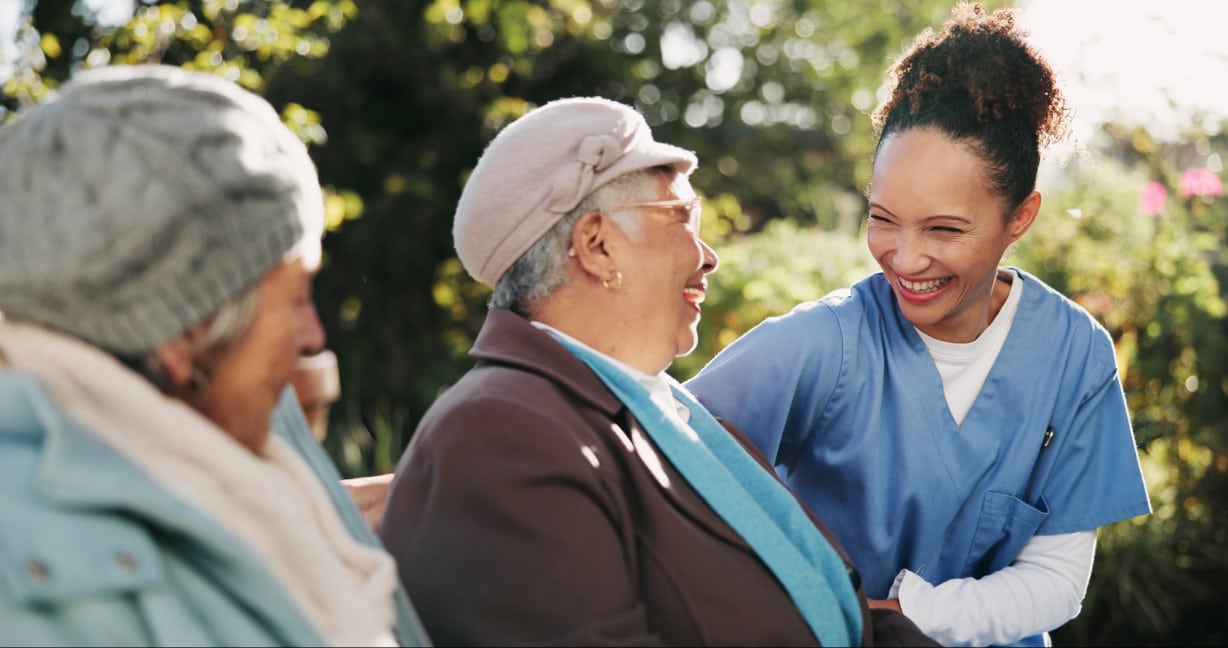 A nurse laughing with an older couple in aged care